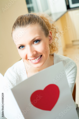 Young woman, reading valentine card at home