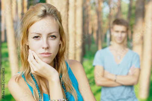 Upset young girl with a boy at the background