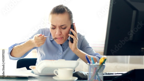 Multitasking businesswoman eating lunch in her office
