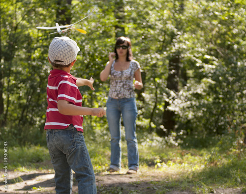 Mother and son launching toy glider outdoors
