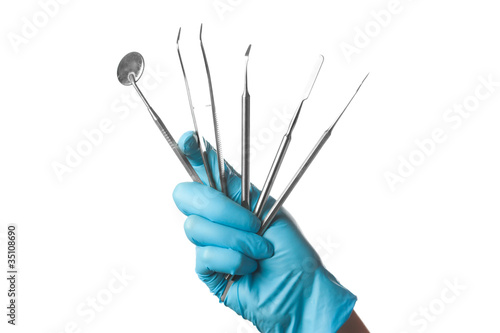 hand in blue glove holding dental tools isolated on white