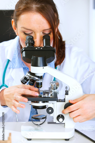 Woman researcher using microscope in medical laboratory. Closeup
