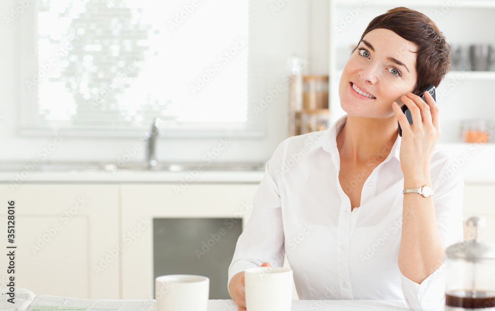 Woman with mobile phone and coffee in kitchen Woman with mobile phone and coffee in kitchen