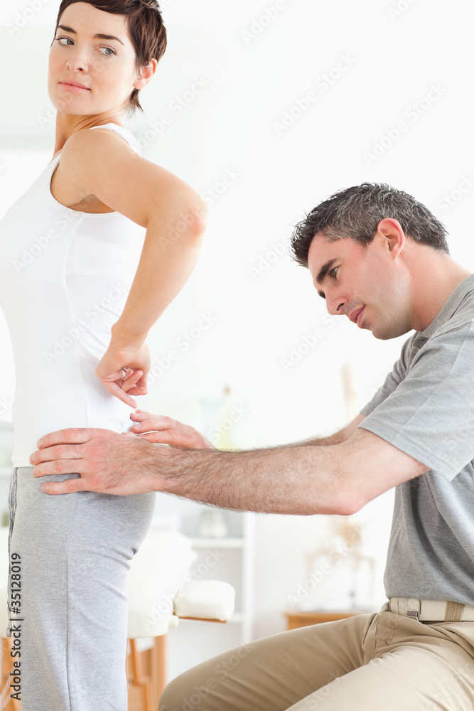 Obraz premium Chiropractor examining a brunette woman's back
