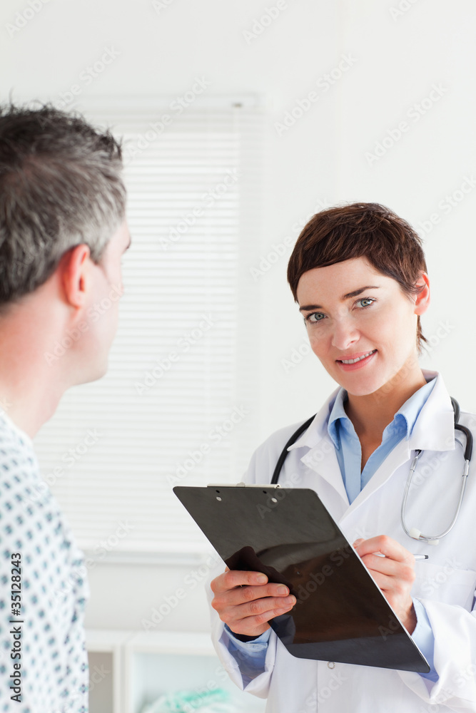 Doctor talking to a male patient while holding a chart Doctor talking to a male patient while holding a chart
