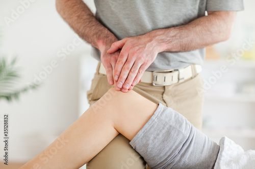 Chiropractor massaging a cute woman's knee
