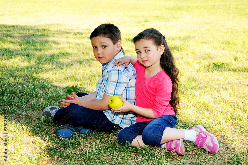 The boy with the girl play sitting on a grass