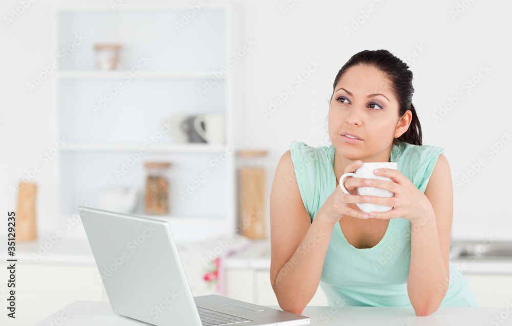 Thoughtful young woman with laptop and coffee Thoughtful young woman with laptop and coffee