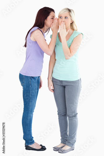Cute woman telling friend a secret