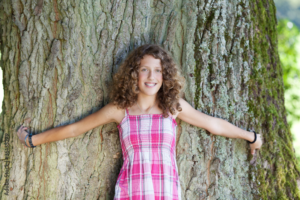lachendes junges mädchen steht vor einem baum lachendes junges mädchen steht vor einem baum