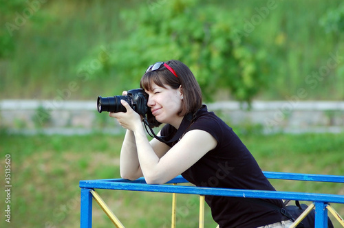 Yong woman photographer with camera in park photo