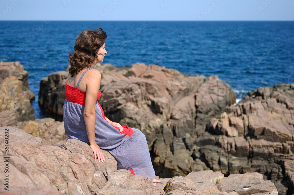 Woman sitting on rock near sea