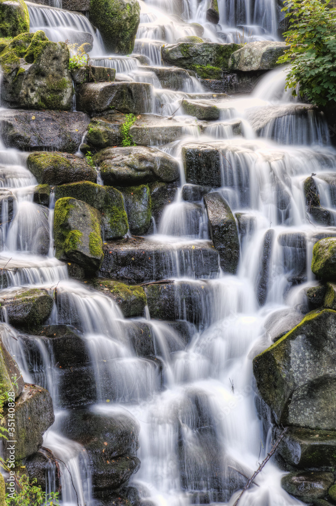 Beautiful waterfall cascades over rocks in lush forest landscape Beautiful waterfall cascades over rocks in lush forest landscape