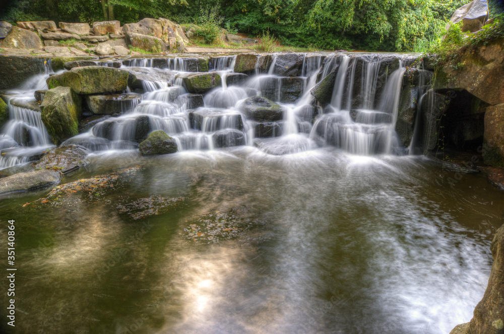 Fototapeta premium Beautiful waterfall cascades over rocks in lush forest landscape