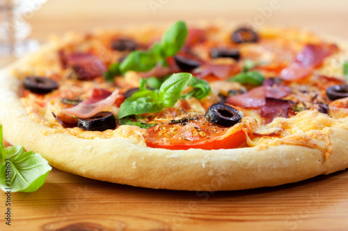 Pizza with tomatoes and ham on wooden background