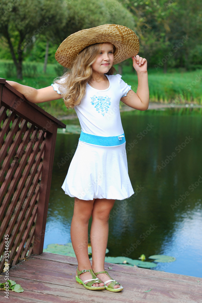 The little girl in a white dress and in a straw hat