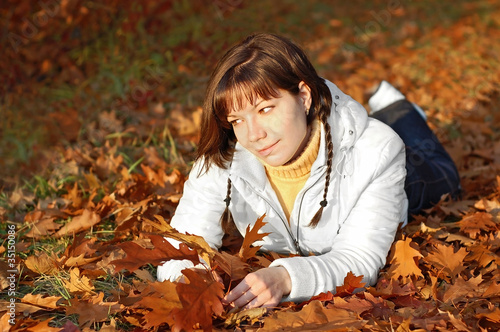Young woman in autumn orange leaves in forest