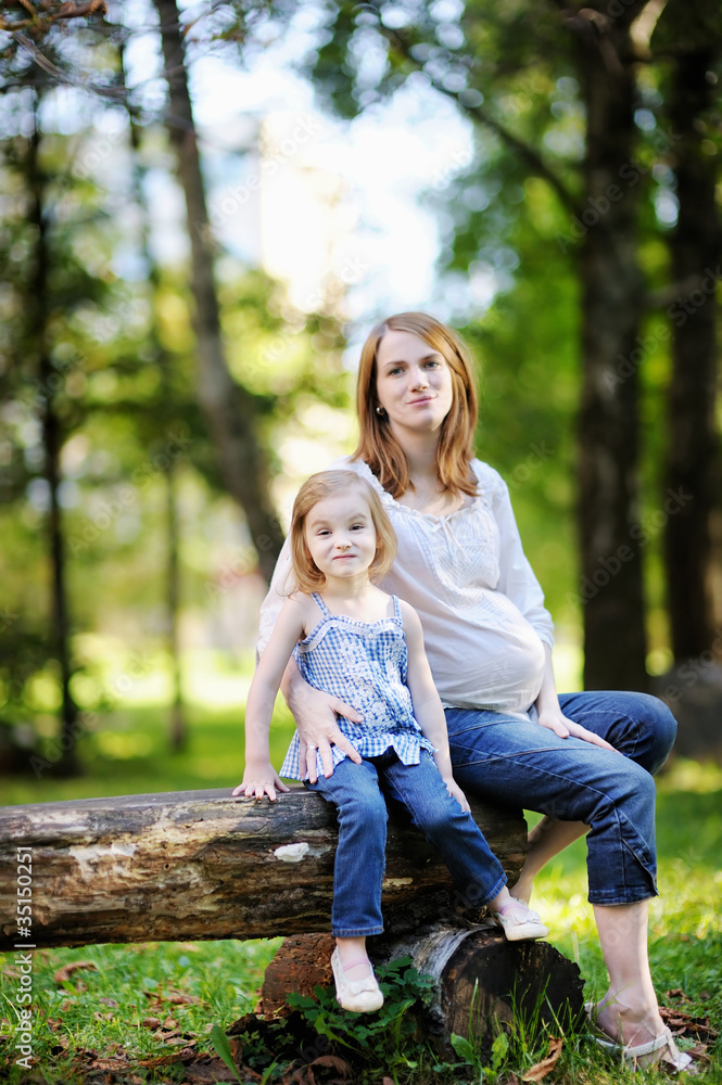 Fototapeta premium Little girl and her pregnant mother outdoors