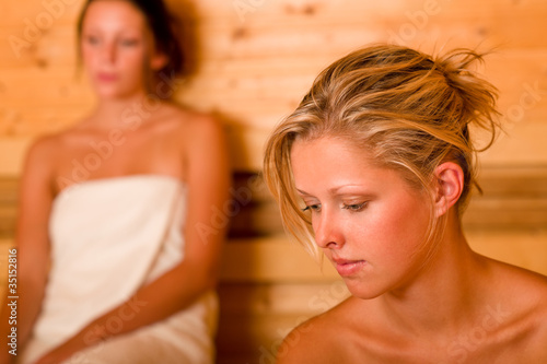 Sauna two women relaxing sweating covered towel