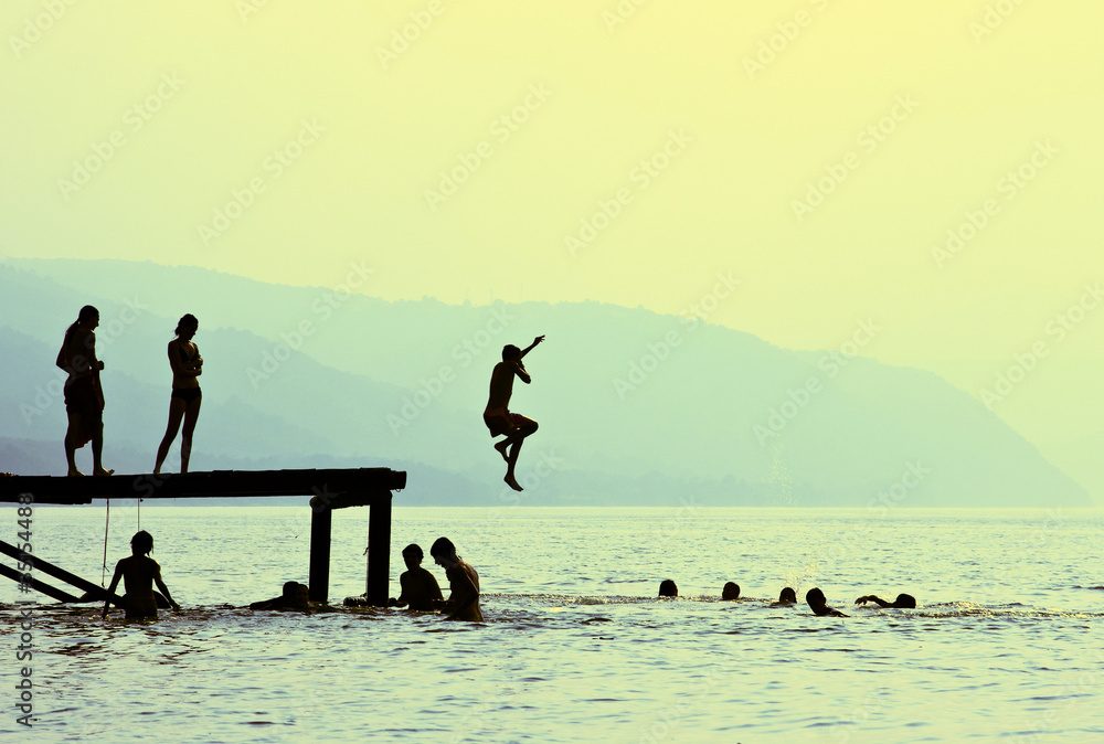 Naklejka premium silhouettes of children jumping off the dock