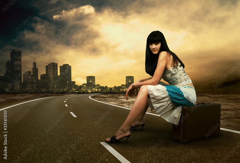 Fototapeta premium Young woman waiting on the road with her vintage baggage