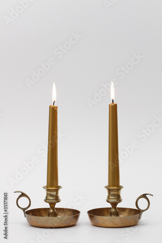 two burning candles in brass chambersticks