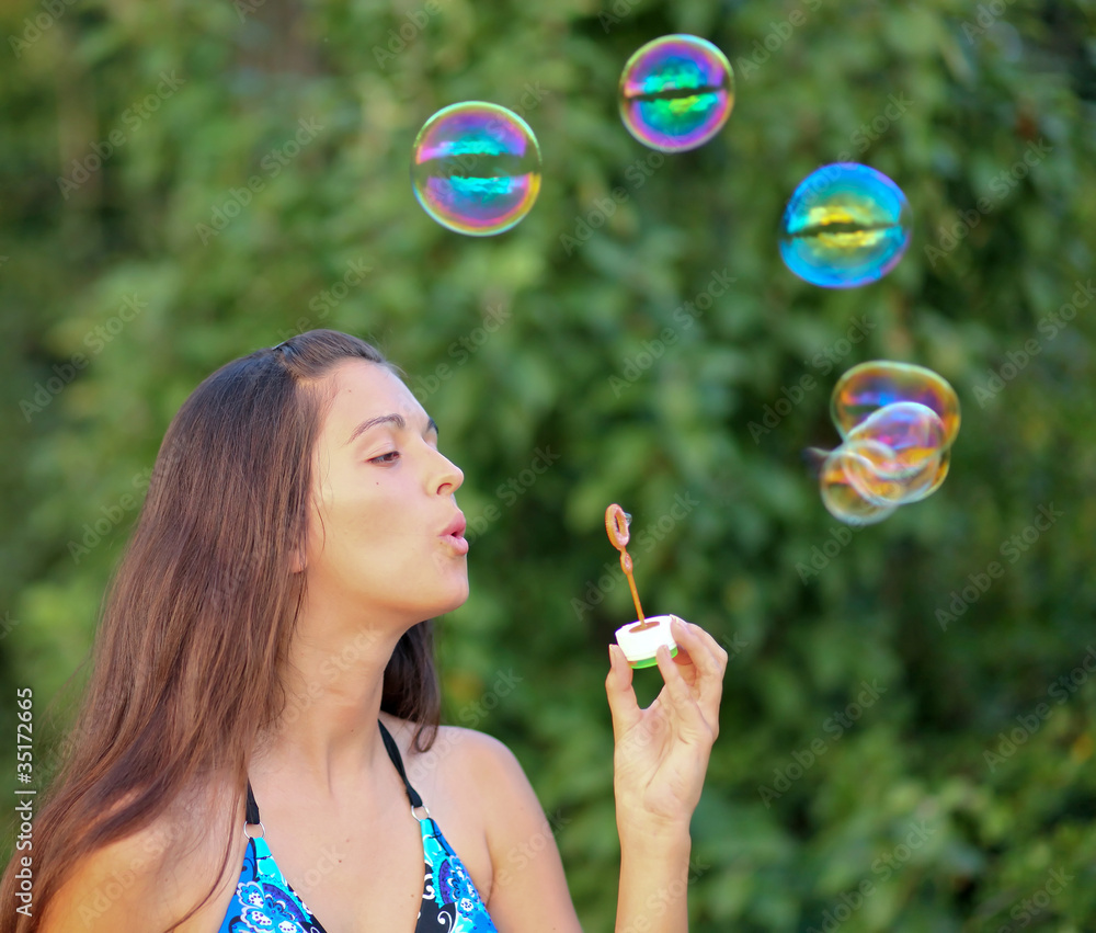 Young girl inflating colorful soap bubbles Young girl inflating colorful soap bubbles