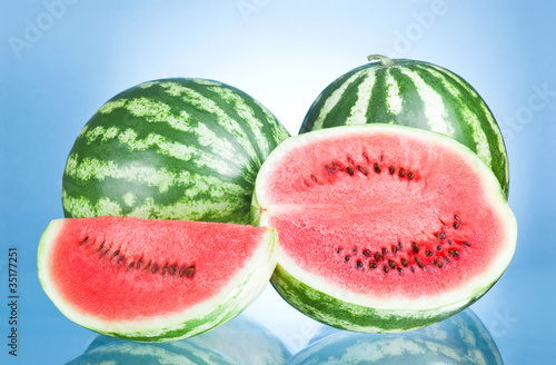 Two Whole watermelon, half and Slice on a blue background