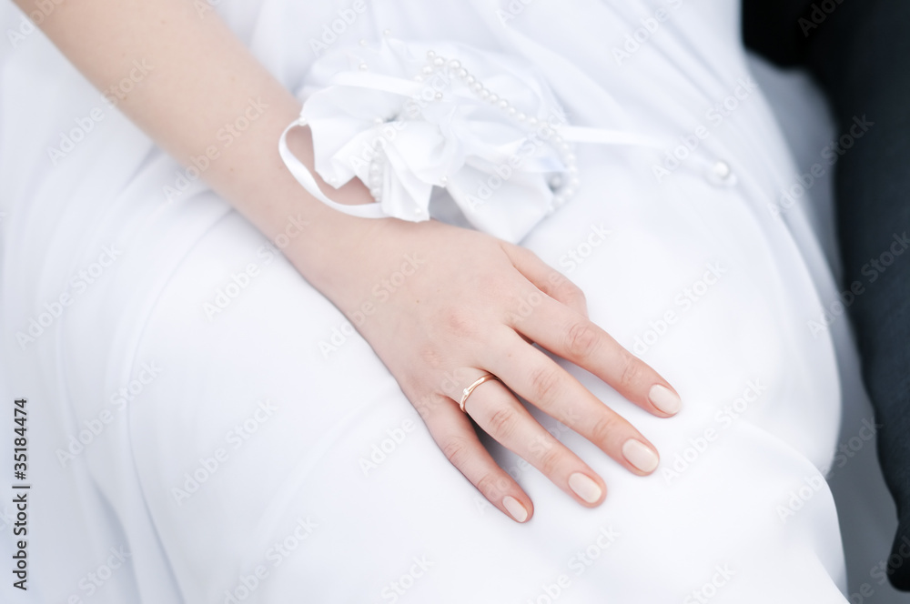 Beautiful bride's hand laying on a white dress Beautiful bride's hand laying on a white dress