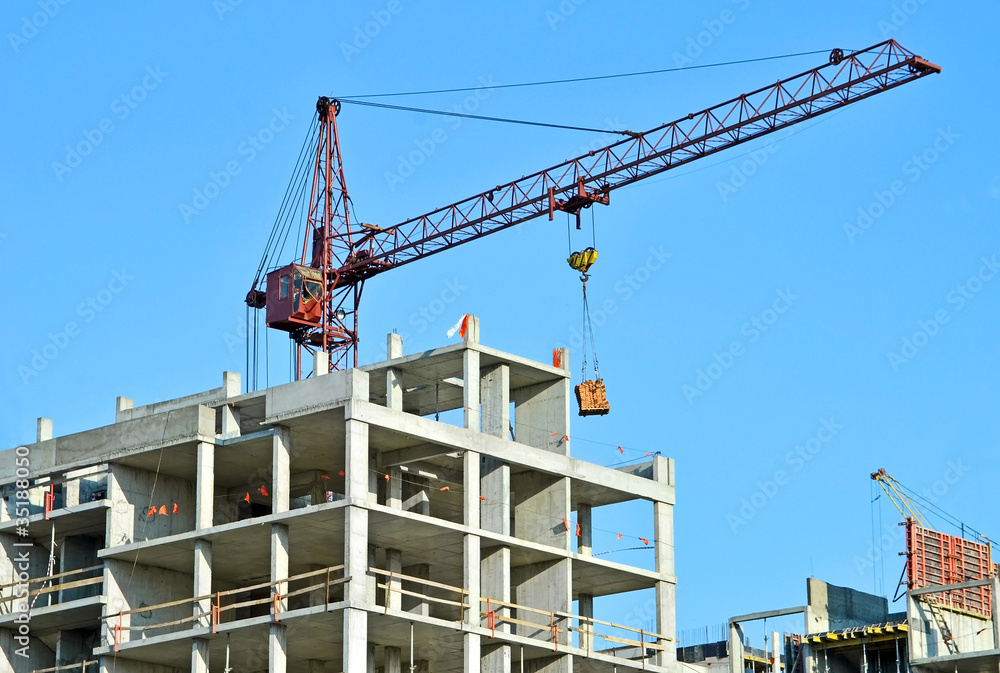 Crane and building construction site against blue sky