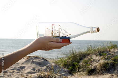 Man is holding miniature ship in bottle