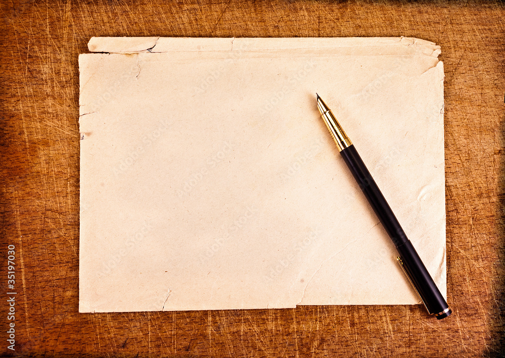 Ink pen and an old torn envelope on a wooden background. Ink pen and an old torn envelope on a wooden background.