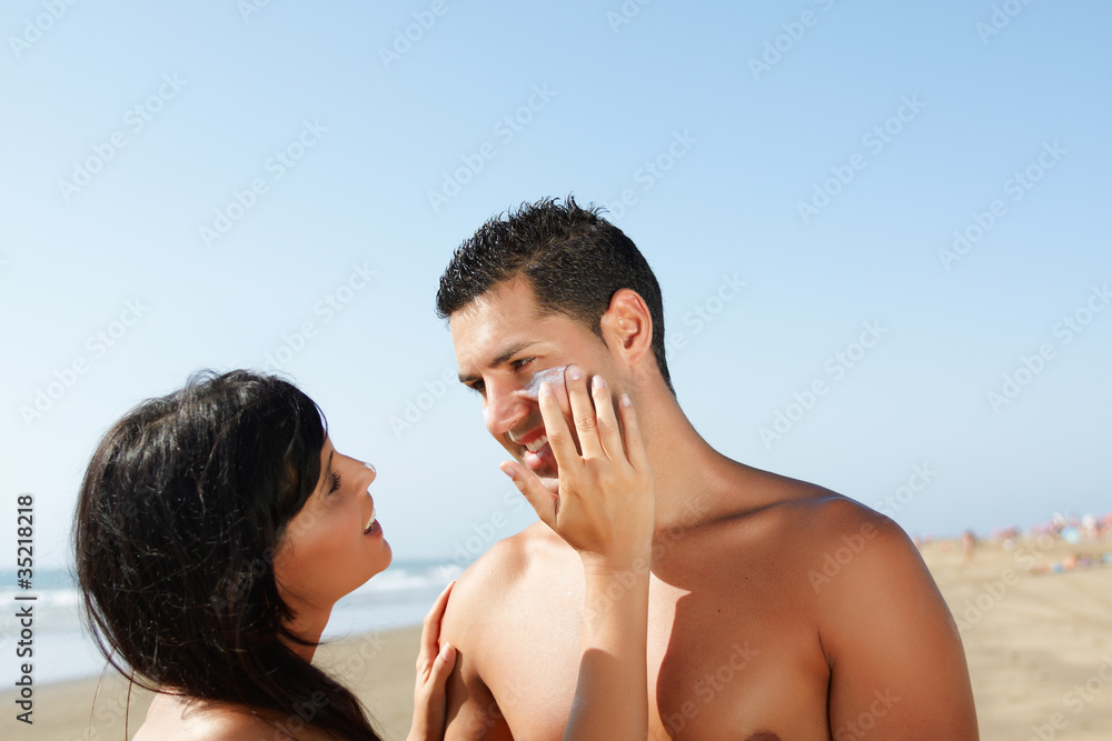 couple on the beach putting on cream couple on the beach putting on cream