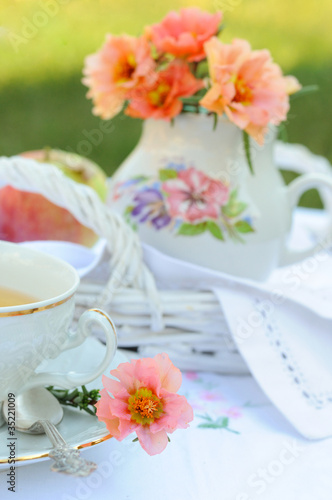 Still life with purslane flowers in a jug and a cup of tea.