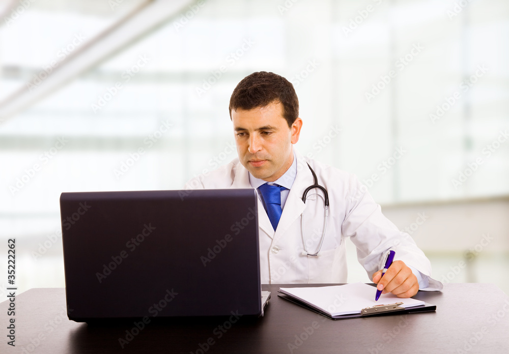 A male doctor working at the desk in hospital office