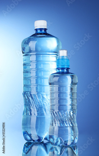 Two plastic bottles of water on blue background