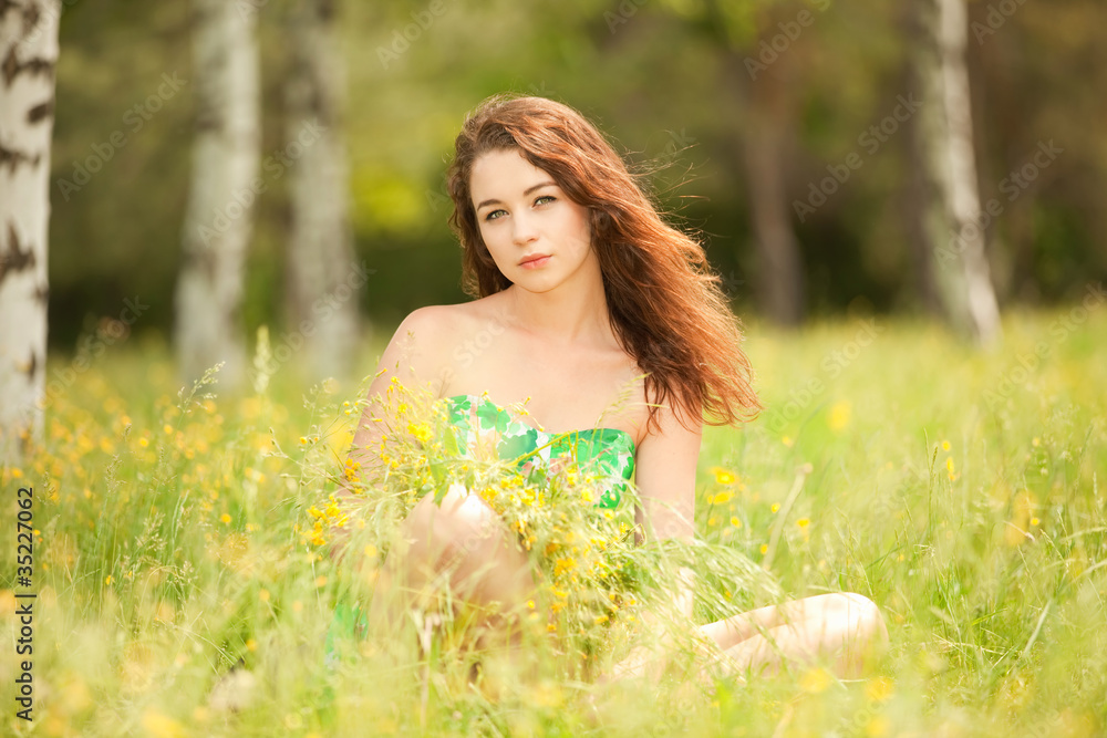 Young redhead woman in the park with flowers Young redhead woman in the park with flowers