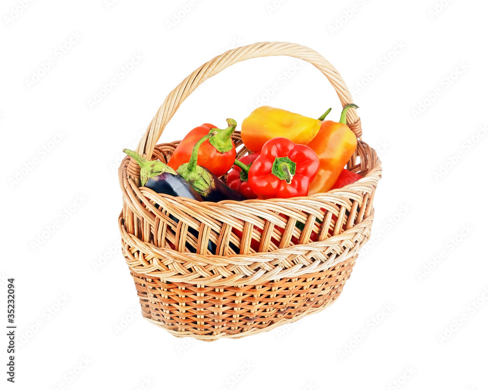 Fresh sweet red pepper and eggplant in a wattled basket on white Fresh sweet red pepper and eggplant in a wattled basket on white