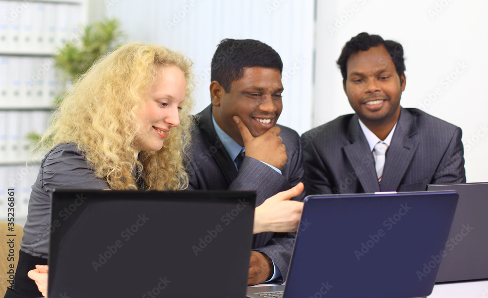 Interracial business team working at laptop in a Interracial business team working at laptop in a