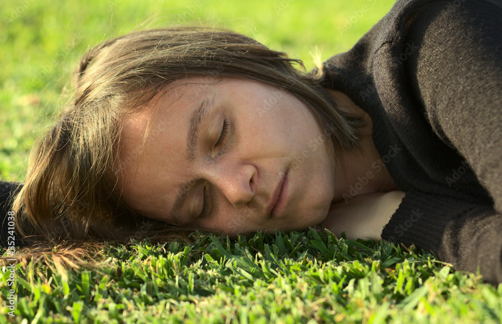 Young Caucasian woman sleeping on grass in a park Young Caucasian woman sleeping on grass in a park