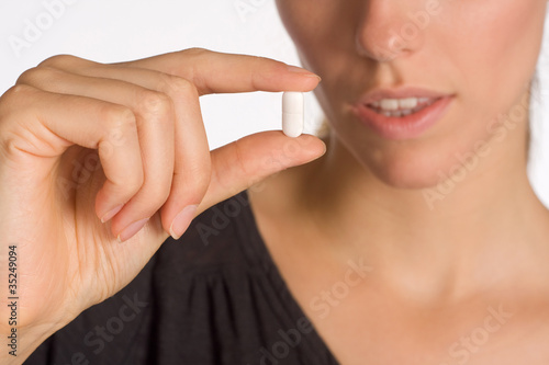 Frau hält Tablette zwischen ihren Fingern