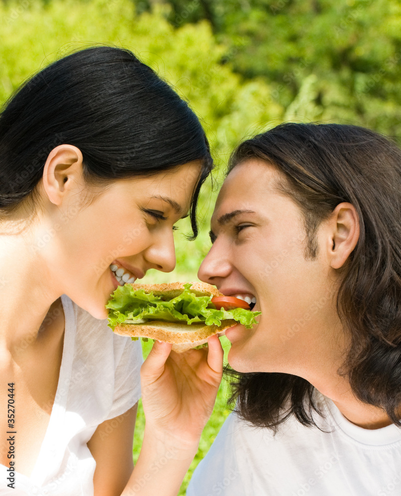 Young happy couple eating together outdoors Young happy couple eating together outdoors