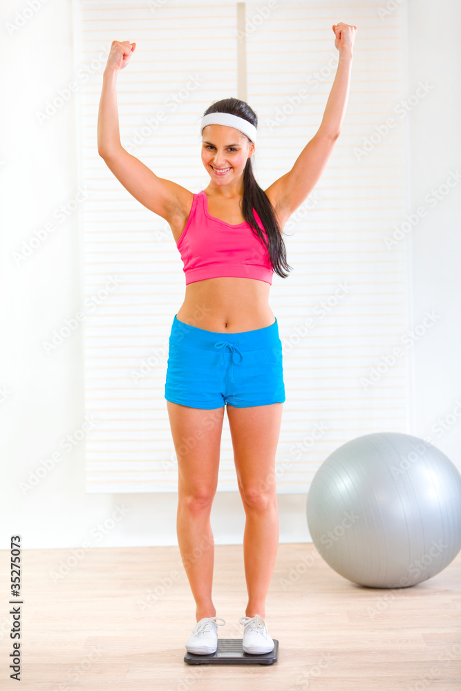 Slim girl standing on weight scale and rejoicing weight loss Slim girl standing on weight scale and rejoicing weight loss