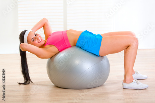 Smiling fitness girl doing abdominal crunch on fitness ball