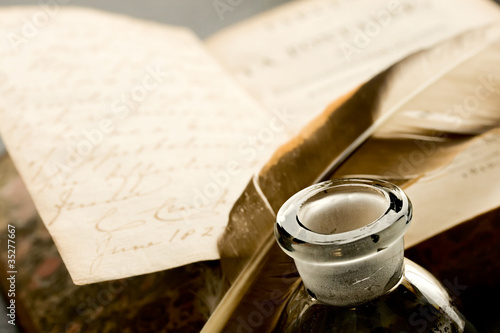 Old book with feather and inkpot