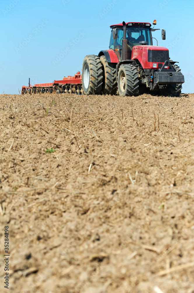 Fototapeta premium Ploughing tractor at field cultivation work