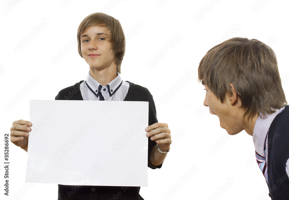 One boy looks surprisingly at another one holding a white poster One boy looks surprisingly at another one holding a white poster
