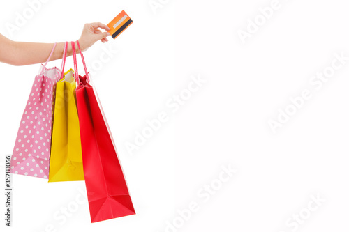 Female hand holding shopping bags and credit card, isolated on w