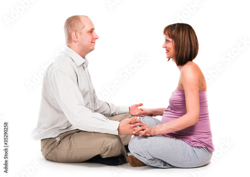 The husband and the pregnant wife keep in a yoga pose..