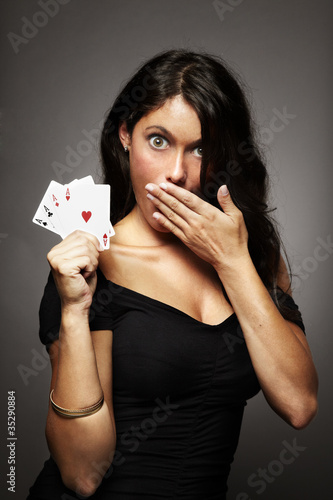 mujer jugando al poker con poker de ases en la mano sorprendida photo